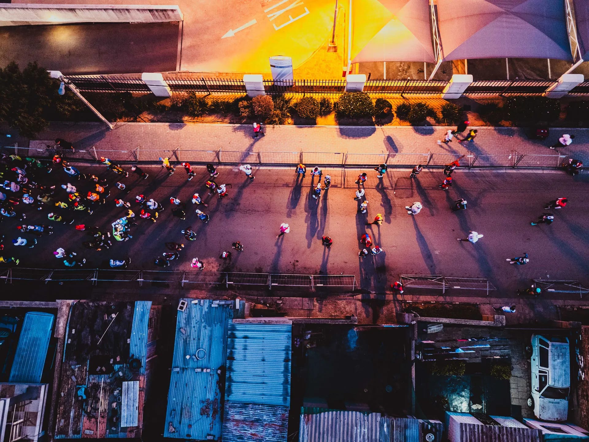 Top-down view of marathon runners on a paved road casting long shadows during an early morning race.